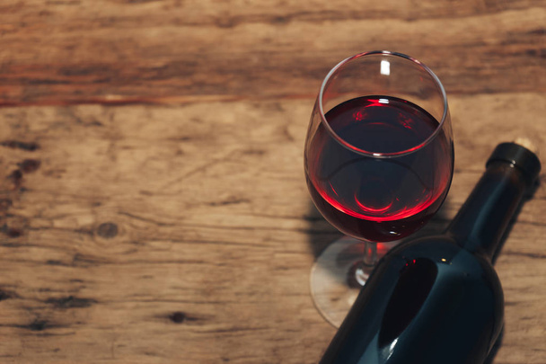 Бутылка красного вина и бокал вина на старом деревянном столе
.  - Фото, изображение