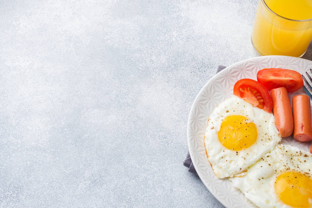 Fried eggs and sausage, tomatoes on a plate. concept breakfast. - Foto, afbeelding