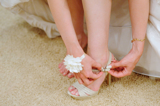 The bride fastens the belt on the shoe. - Фото, изображение