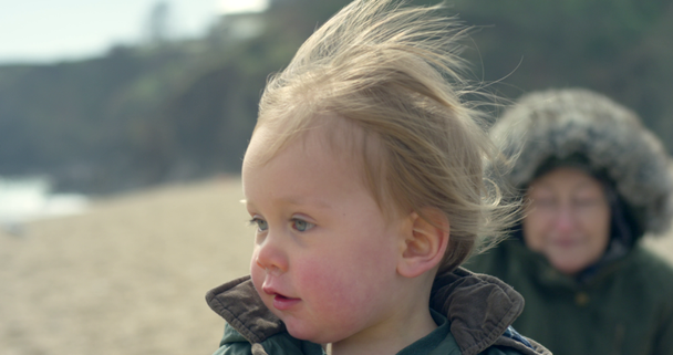 A cute little boy is on the beach with his grandmother, he starts running in 120fps slow motion. - Záběry, video