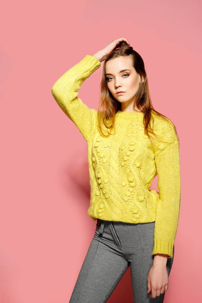 Beautiful female model wears casual comfrotable sweater, poses against pink background. Copyspace - Photo, image