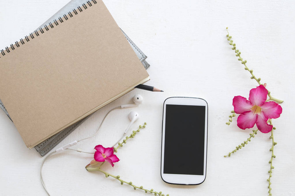 Notebook planner i telefon komórkowy dla firmy współpracują z różowe kwiaty dekoracja płaskich lay stylu na białe tło - Zdjęcie, obraz