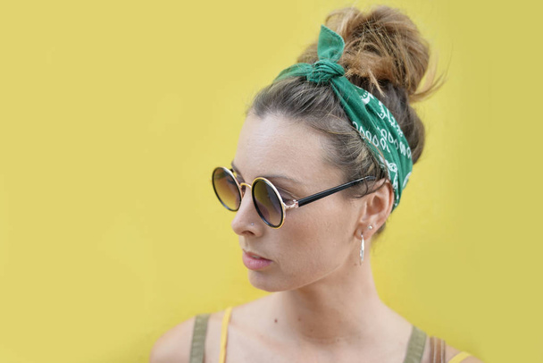 Portrait of stylish young woman in sunglasses outdoors on yellow background - Photo, Image