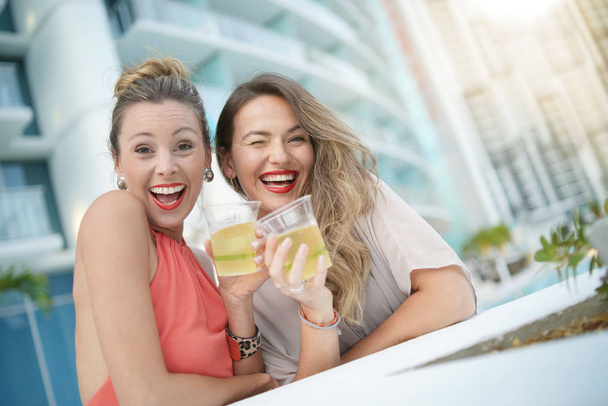 Dois amigos divertidos atraentes festejando com bebidas no bar no último piso da cidade
 - Foto, Imagem