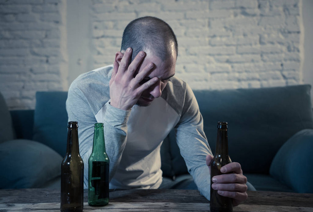 Young sad drunk men drinking beer and alcohol feeling wasted, lonely and desperate in pain and emotional stress. People and Alcohol abuse, addiction and man depression concept. Dramatic light - Foto, imagen