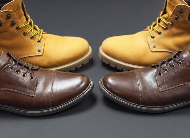 Класичне коричневе шкіряне чоловіче взуття та жовті чоботи з натурального нубука на сіро-чорному фоні зверху плоский простір для копіювання. Модна чоловіча концепція, справжнє шкіряне взуття, продаж, магазин
 - Фото, зображення