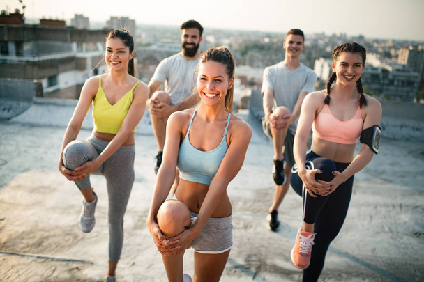 Group of happy fit young people friends training outdoors at sunrise - Фото, зображення