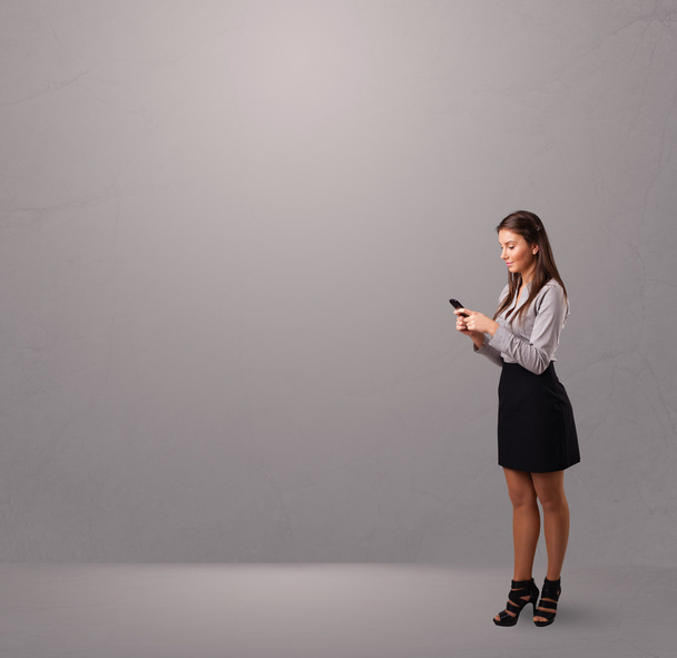 young lady standing and holding a phone with copy space - Foto, imagen