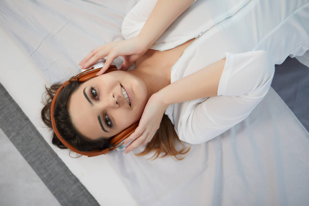 Dziewczyna w łóżku słucha muzyki na słuchawkach - Zdjęcie, obraz