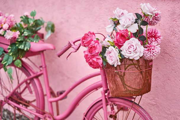 Bright pink bike with flowers in its baskets outdoors - Zdjęcie, obraz