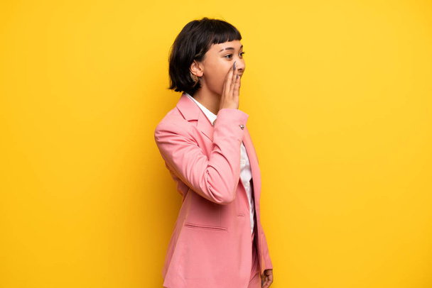 Mujer moderna con traje de negocios rosa gritando con la boca abierta hacia el lateral
 - Foto, Imagen