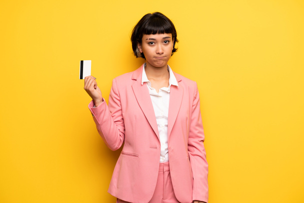 Современная женщина в розовом деловом костюме держит кредитную карту
 - Фото, изображение