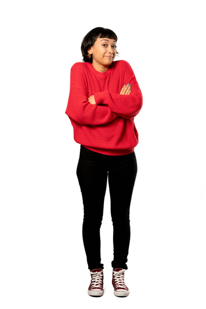 Полнометражный снимок девушки с короткими волосами в красном свитере, делающей сомнительный жест, поднимая плечи на изолированном белом фоне
 - Фото, изображение