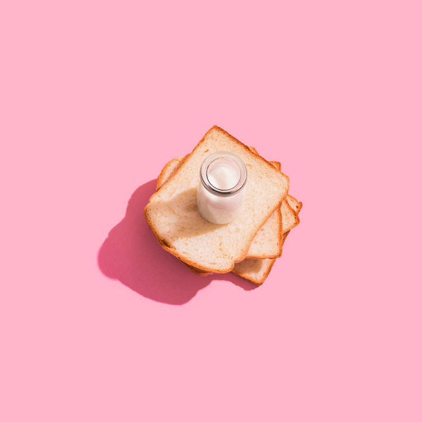 Una rebanada de pan de centeno y leche sobre un fondo rosado
 - Foto, Imagen
