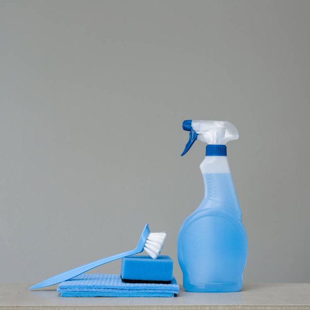 Cleaning blue spray bottle with plastic dispenser, sponge, 	scrubbing brush for dish and cloth for dust  on grey background. Cleaning tools. Copy space. - Foto, afbeelding