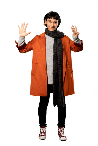 A full-length shot of a Short hair woman with coat counting eight with fingers over isolated white background - Foto, imagen
