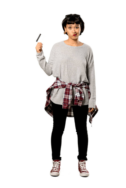 Un full-length shot di una giovane donna con i capelli corti che prende una carta di credito senza soldi su sfondo bianco isolato
 - Foto, immagini