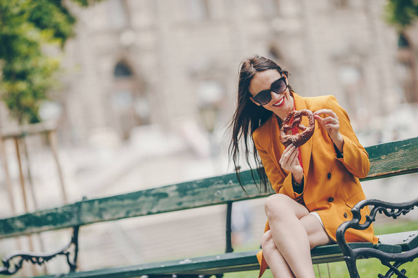 Beautiful young woman holding pretzel and relaxing in park - Foto, Imagem