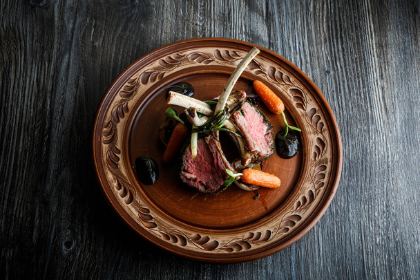 pohled shora velké kousky šťavnaté grilované žebra s masem steak s omáčkou a grilovaná Karotka na hliněné destičky na dřevěný stůl - Fotografie, Obrázek