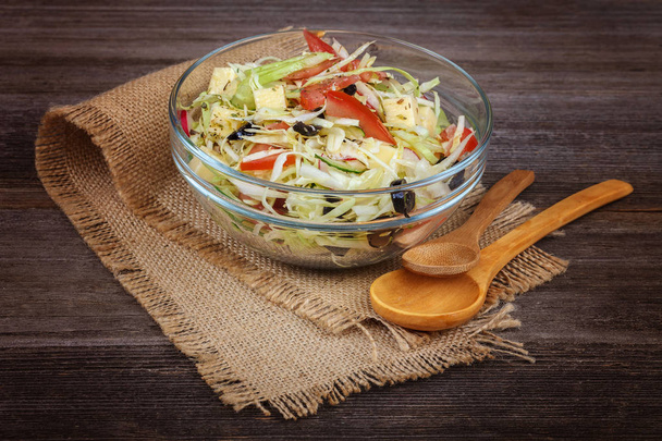 Fresh vegetables and vegetable salad in dishes on wooden background. - Fotó, kép