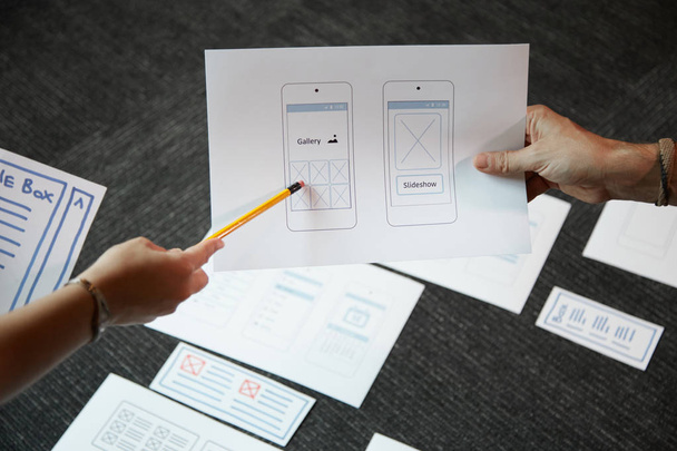 Σχεδιαστή UI συζητάμε ιδέες για την κινητή εφαρμογή διασύνδεσης με τον πελάτη - Φωτογραφία, εικόνα