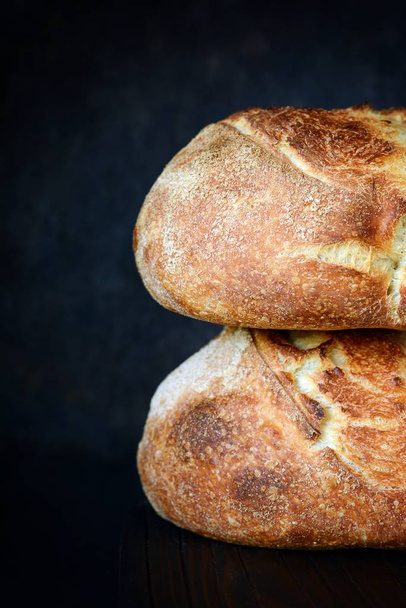 Fresh homemade bread on a dark background, on whole wheat flour. French bread round shape. Bread baking. Unleavened bread - Zdjęcie, obraz