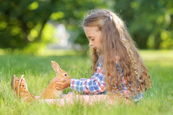 schattig meisje met kleine konijntje in zomer park - Foto, afbeelding