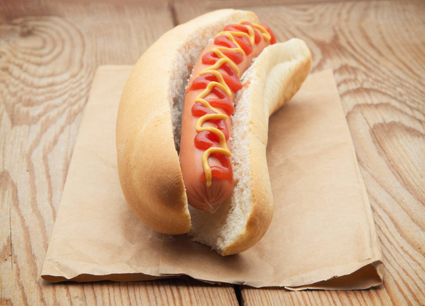 Tasty hot dog on wooden table - Foto, afbeelding