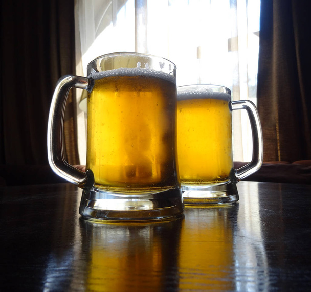 Pełen projekt szklanki piwa na drewnianym stole   - Zdjęcie, obraz