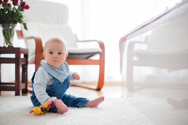 Cute little toddler baby boy, playing at home on the floor in bedroom, baby reflection on the bed, smiling happily - 写真・画像