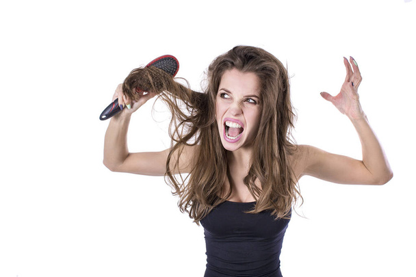 Frau mit dickem braunem Wuschelhaar versucht Haare zu kämmen, scheitert aber. Haarpflege-Konzept. - Foto, Bild