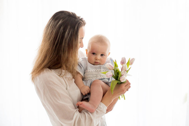 Cute baby boy,  holding bouquet of fresh tulips for mom. Happy Mother's Day - Foto, Bild
