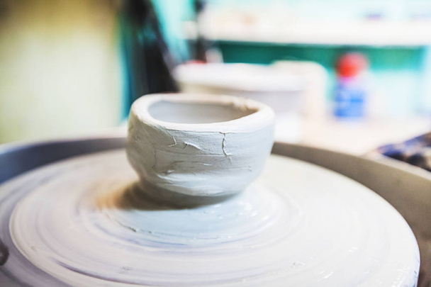 Clay bowl on pottery wheel at workshop. - Foto, afbeelding