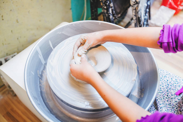 Pottery workshop for children - Child hands shaping clay at wheel - Photo, Image