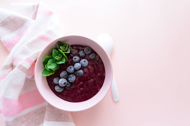 healthy berry smoothie bowl with banana on pink background. Vegetarian food or detox concept. Selective focus - Valokuva, kuva