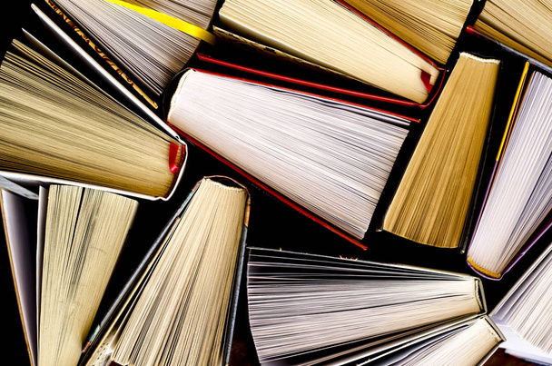 Много красочных толстых открытых книг стоят на темном фоне
 - Фото, изображение