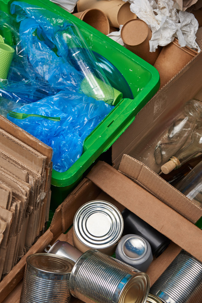 sorted trash of cardboard, glass and plastic bottles, polyethylene, cups, iron cans - Fotó, kép