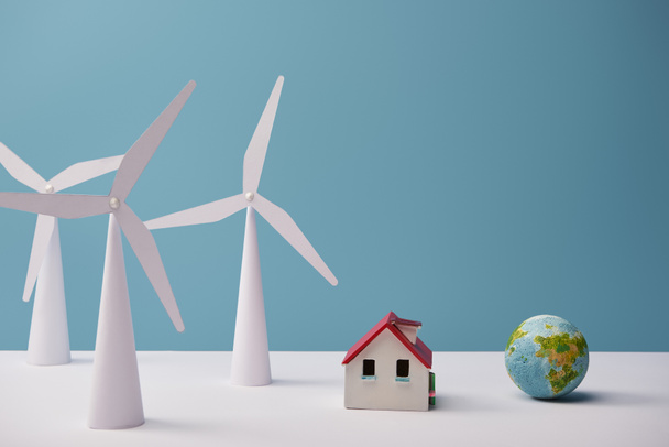 windmill and house models with small globe on white table and blue background - Photo, Image