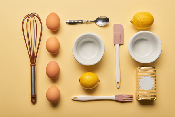 плоский ліжко з посудом для приготування їжі, лимонами, маслом та яйцями на жовтому фоні
 - Фото, зображення