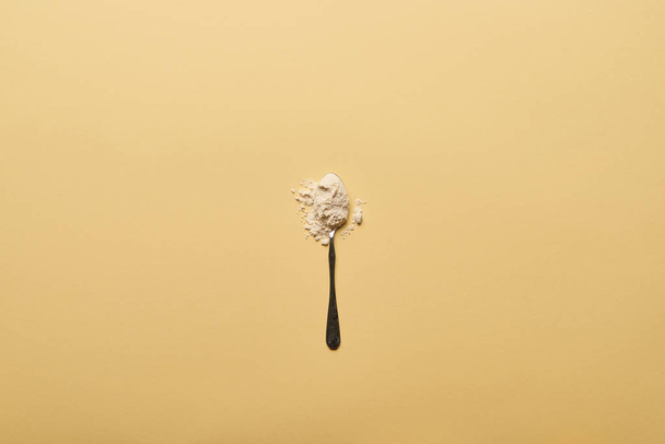 top view of spoon with scattered flour on yellow background - Fotografie, Obrázek