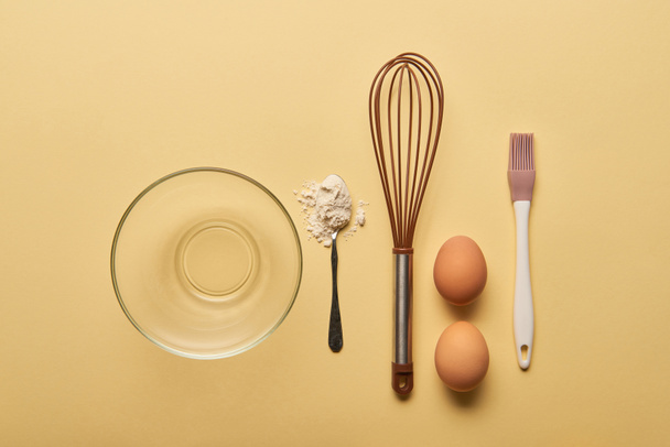 flat lay with bowl, spoon with flour, balloon whisk, eggs and bakery brush - Photo, Image