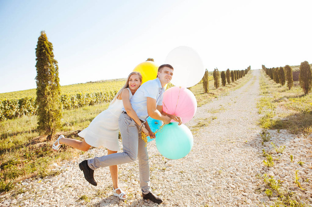 lovers are laughing and hugging on a walk in the summer, holding balloons - Foto, imagen