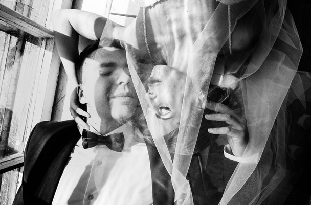 stylish bride and groom at a wedding photo session in the studio, a couple in love is lying on the floor near the window, the photo is in a hard light - Fotó, kép