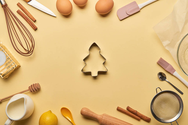 vista superior de los ingredientes de la panadería y utensilios de cocina alrededor del molde de masa en forma de árbol
 - Foto, Imagen