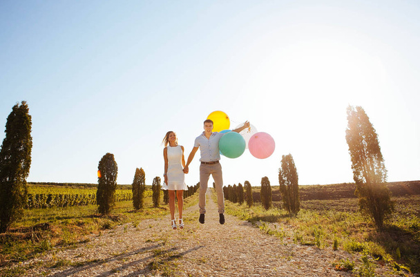 amantes estão rindo e abraçando em um passeio no verão, segurando balões
 - Foto, Imagem
