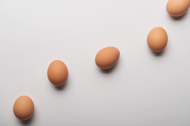 top view of organic eggs arranged in wavy line on grey background  - Φωτογραφία, εικόνα