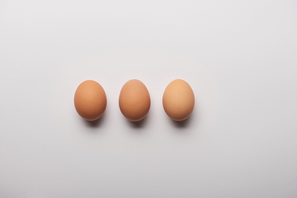 flat lay with three organic eggs on grey background  - Zdjęcie, obraz