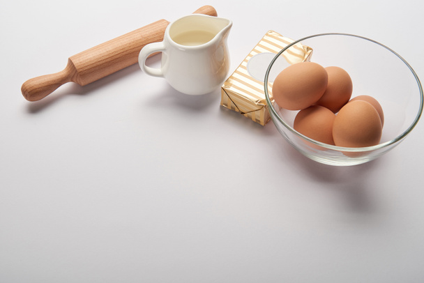 valssaustappi, purkki maidon, voin ja munien kanssa kulhossa harmaalla pohjalla ja kopiotila
 - Valokuva, kuva