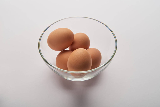 αυγά σε διαφανές γυάλινο μπολ σε γκρι επιφάνεια - Φωτογραφία, εικόνα