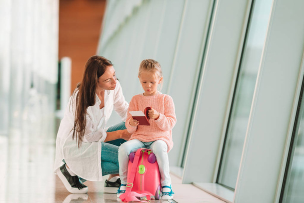 Família feliz no aeroporto sentada na mala com cartão de embarque à espera de embarque
 - Foto, Imagem